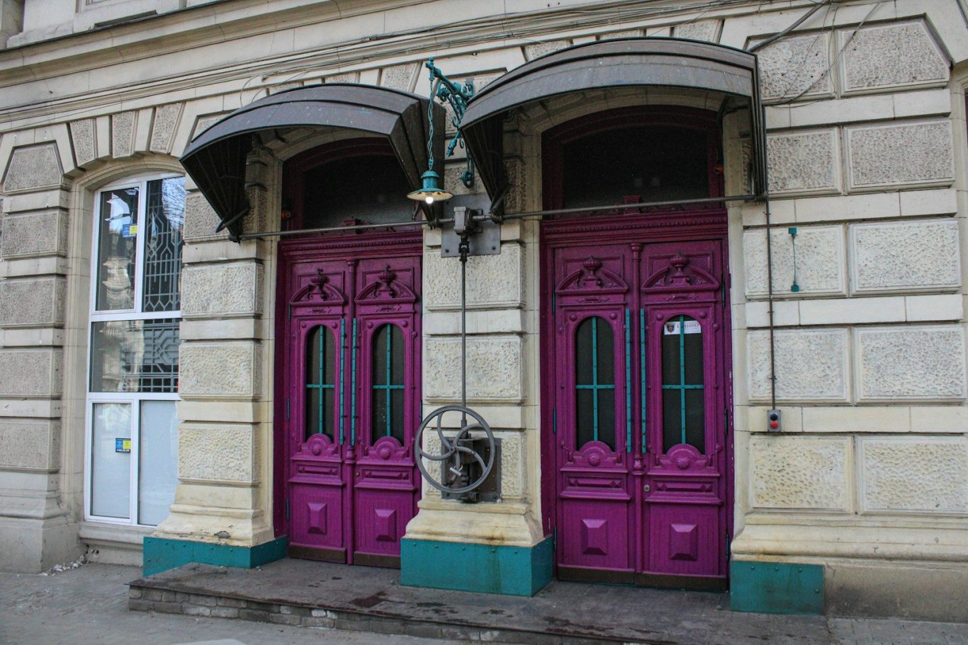 Pair of ornate purple doors with decorative features, flanked by stone walls.